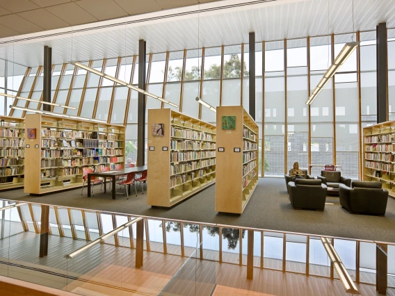 Library reading room with bookshelves and tables and chairs.